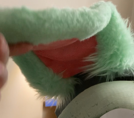 Grünes Schlappohr eines Fursuits mit längerem Fell am Ansatz und kürzerem Fell überall sonst