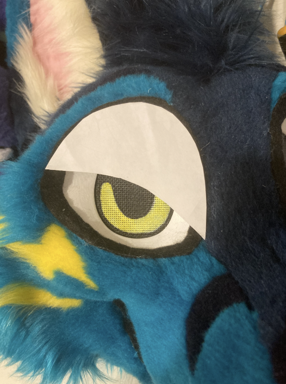 Papiervorlage auf dem Auge eines türkisen Folf-Fursuit-Kopfs, wodurch er wütend aussieht